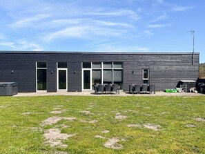A modern building with large windows, outdoor seating, and a grill area.
