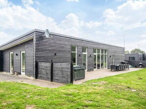 A modern building with a flat roof, large windows, and a patio area with outdoor furniture. - 4 Star Holiday Home in Glesborg (Glesborg)
