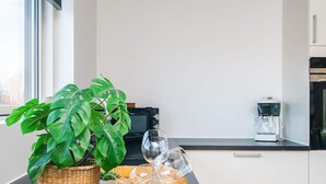 A kitchen with a large window, a coffee maker, and a plant in a basket. - 4 Star Holiday Home in Glesborg (Glesborg)