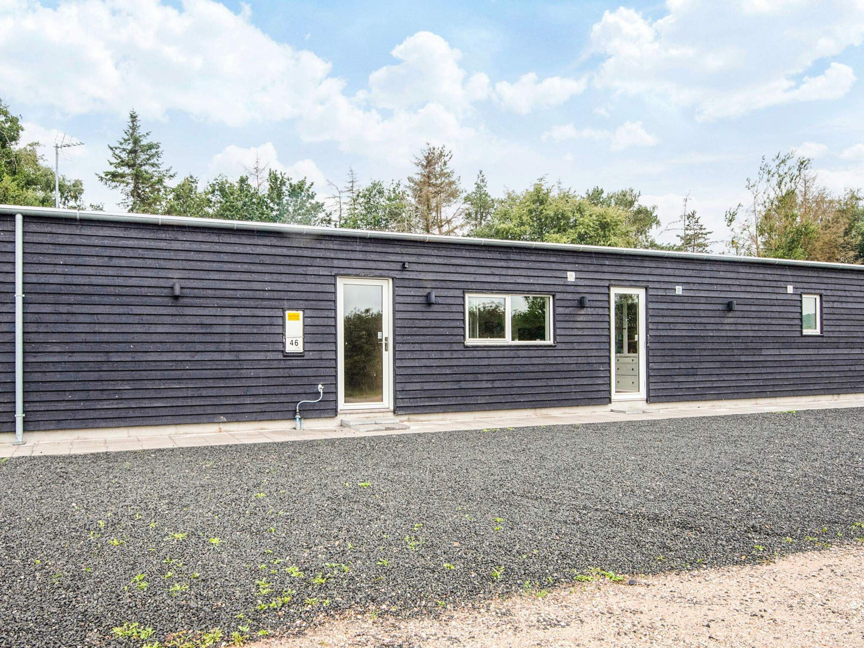 Een laag gebouw met een donkere gevel, een deur en een raam.