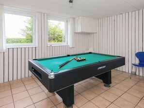 A pool table with balls and cues, a chair, and windows with curtains. - 4 Star Holiday Home in Haderslev (Haderslev)