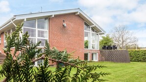 A two-story house with a brick facade, large windows, and a visible chimney.