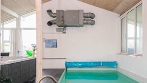 A swimming pool with a blue edge, a metal ladder, and a ceiling fan.