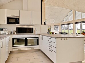 A modern kitchen with built-in appliances, a large island, and a view of the outdoors.