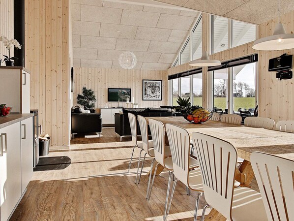 Una cocina moderna con comedor, paredes de madera y ventanas grandes.