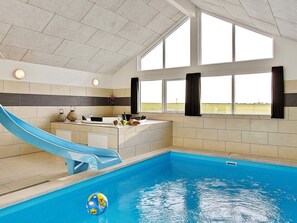 Una piscina con tobogán, una recepción y ventanas grandes.