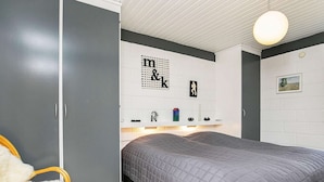 A bedroom with a bed, wardrobe, and a shelf with decorative items. - Elegant Holiday Home in Jerup near Sea (Jerup)