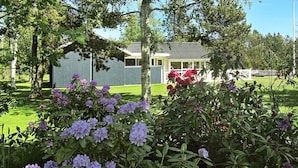A house with a green roof and white walls, surrounded by a well-maintained lawn and flowering bushes. - Elegant Holiday Home in Jerup near Sea (Jerup)