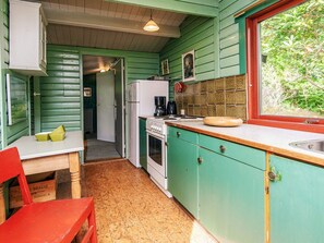 A kitchen with green cabinets, a wooden table, and a window with a view of greenery. - Vintage Holiday Home in Rømø near Sea (Rømø)
