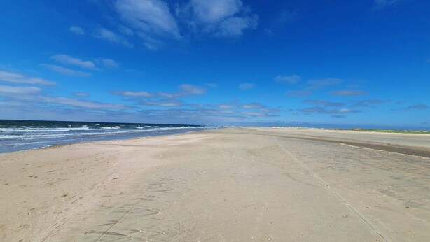 A wide beach with a clear sky and gentle waves.