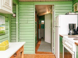 A kitchen with a white refrigerator, a coffee maker, and a striped rug leading to a hallway. - Vintage Holiday Home in Rømø near Sea (Rømø)