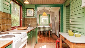 Una cocina con estufa, lavamanos y una mesa de comedor con sillas.