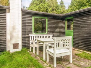A rustic wooden cabin with a bench and a table, surrounded by greenery. - Vintage Holiday Home in Rømø near Sea (Rømø)