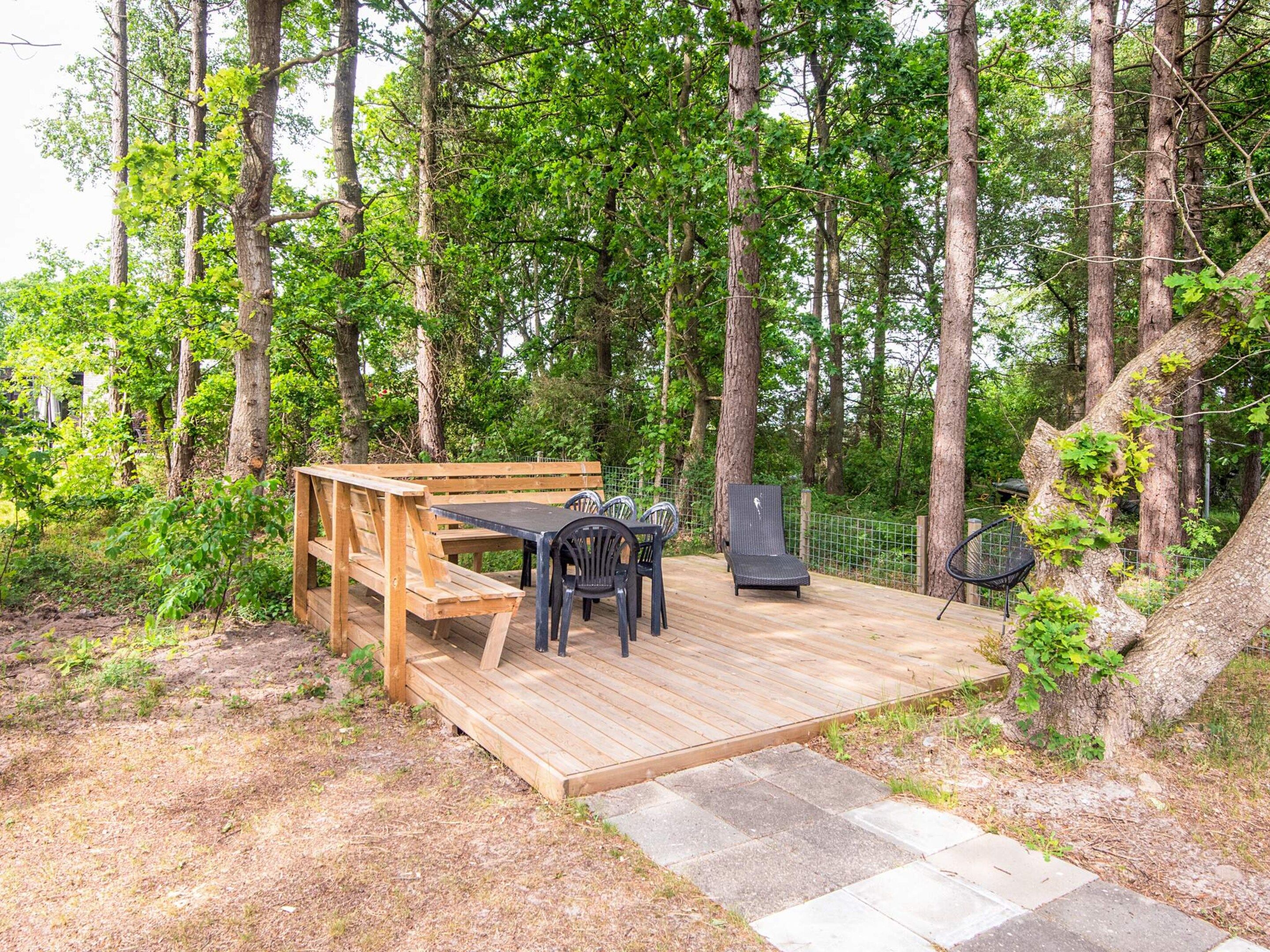 Una terraza de madera con una mesa y sillas, rodeada de árboles.