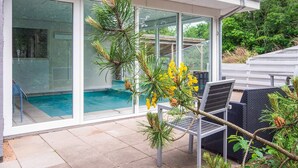 A modern house with a glass-enclosed pool, outdoor seating, and a view of the surrounding greenery. - 7 Person Holiday Home in Orsted (Ørsted)