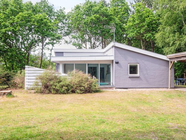 Ein modernes Haus mit überdachter Terrasse, Garage und Rasen.