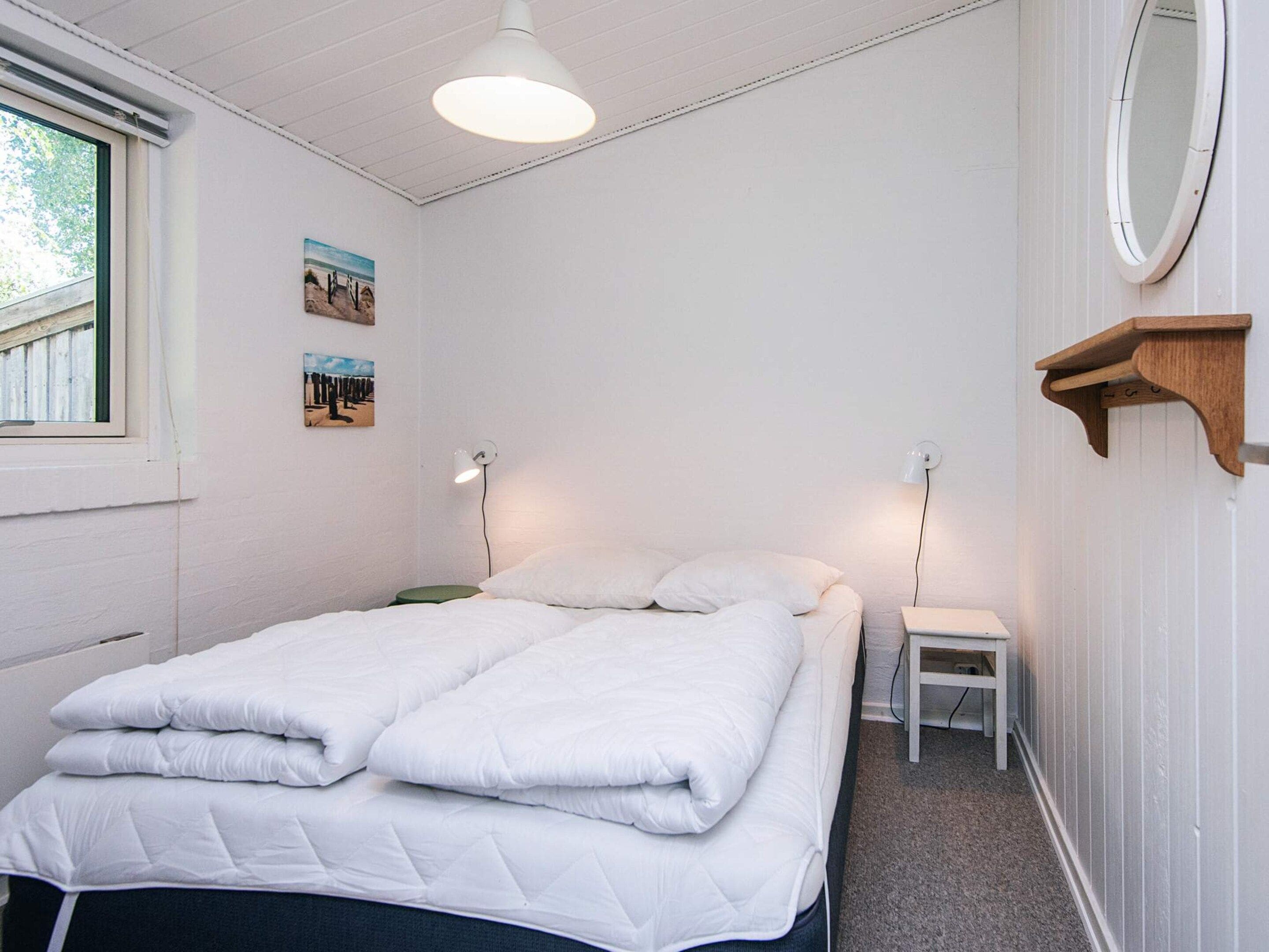 Een slaapkamer met een bed, nachtkastjes, een raam en wandlampen.
