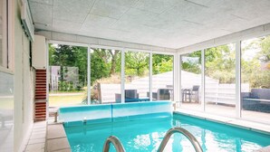 An indoor swimming pool with clear glass walls, a tiled floor, and a metal ladder. - 7 Person Holiday Home in Orsted (Ørsted)