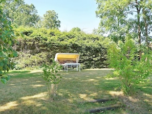 A tent with a yellow canopy set up in a grassy area surrounded by dense foliage.