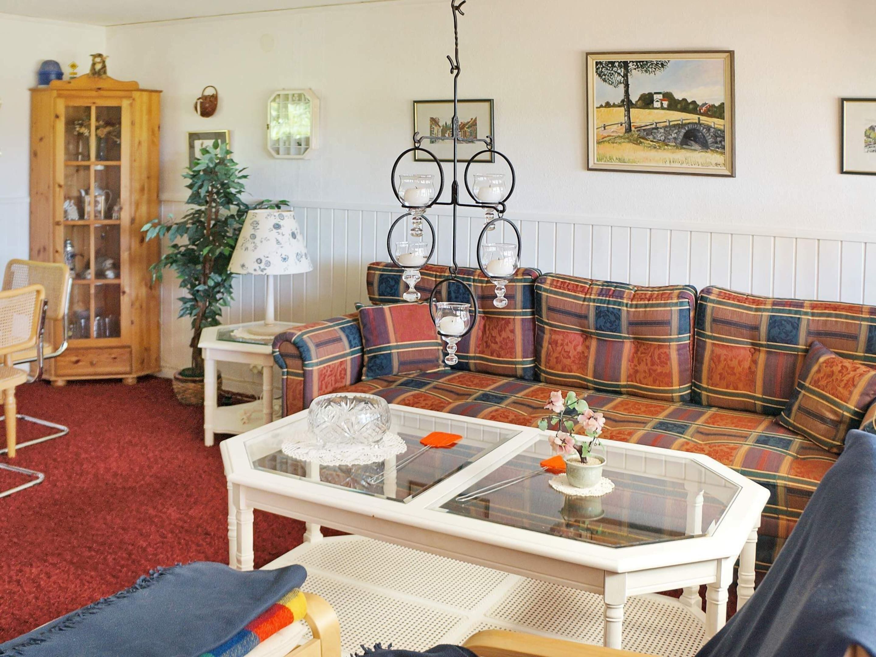 A cozy living room with a plaid sofa, a wooden cabinet, and a glass coffee table.