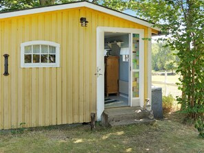 A yellow building with a door leading to a room with a window and a cabinet. - 4 Person Holiday Home in Hastveda (Hästveda)