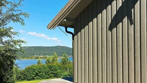 Un edificio de madera con techo inclinado que domina un lago y colinas.