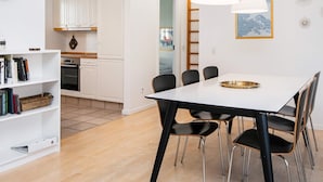 A modern kitchen with white cabinets, a dining table with chairs, and a bookshelf. - 4 Star Holiday Home in Aabenraa (Aabenraa)