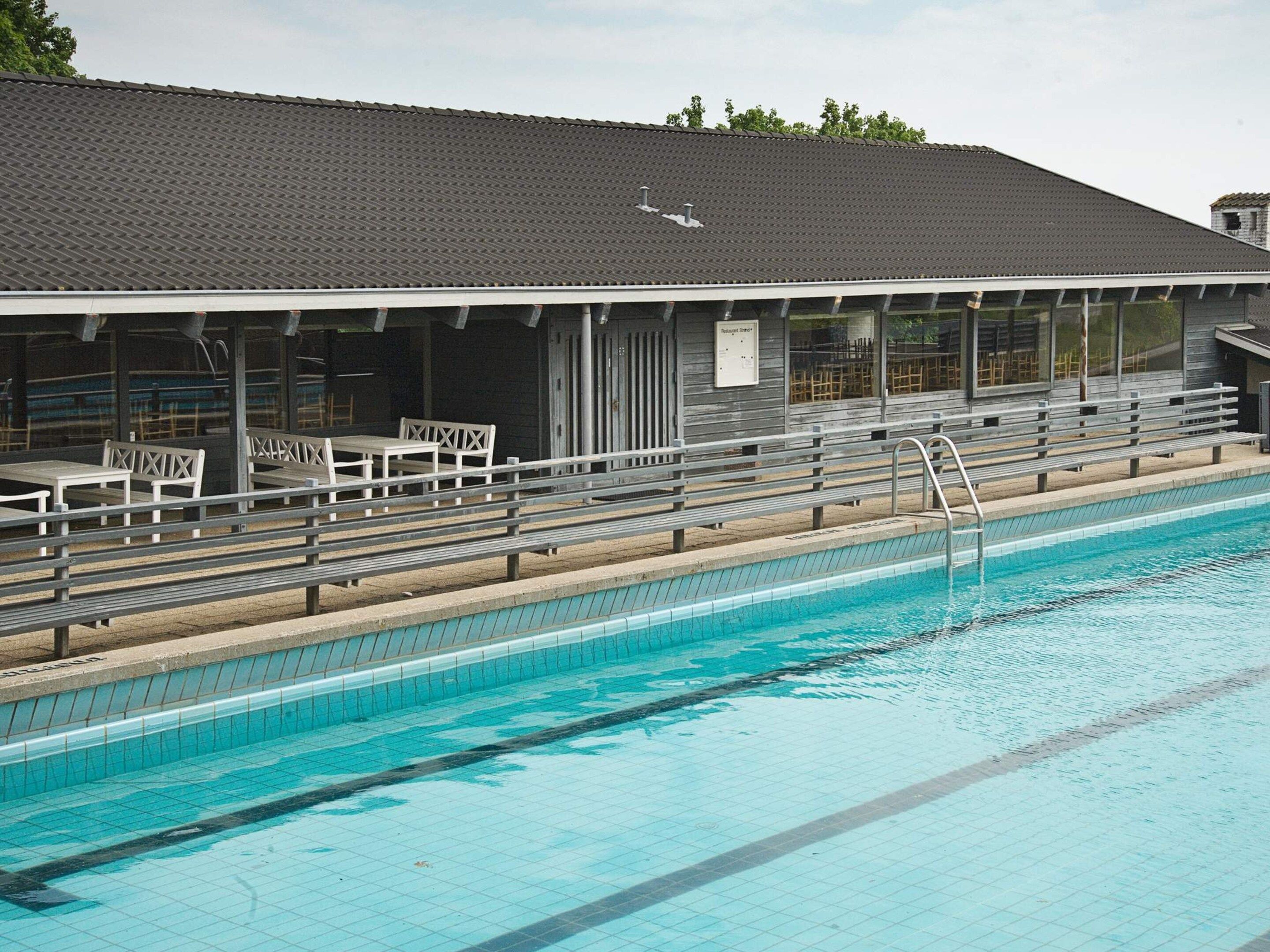 A swimming pool with a covered spectator area and a lifeguard station.