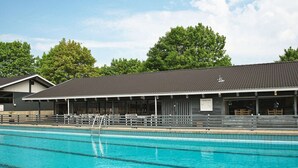 A swimming pool with a tiled deck area and a covered seating section. - 4 Star Holiday Home in Aabenraa (Aabenraa)