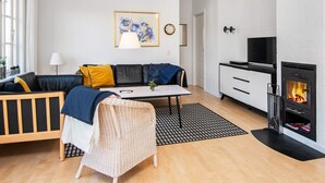A modern living room with a sofa, a dining table, a fireplace, and a television. - 4 Star Holiday Home in Aabenraa (Aabenraa)