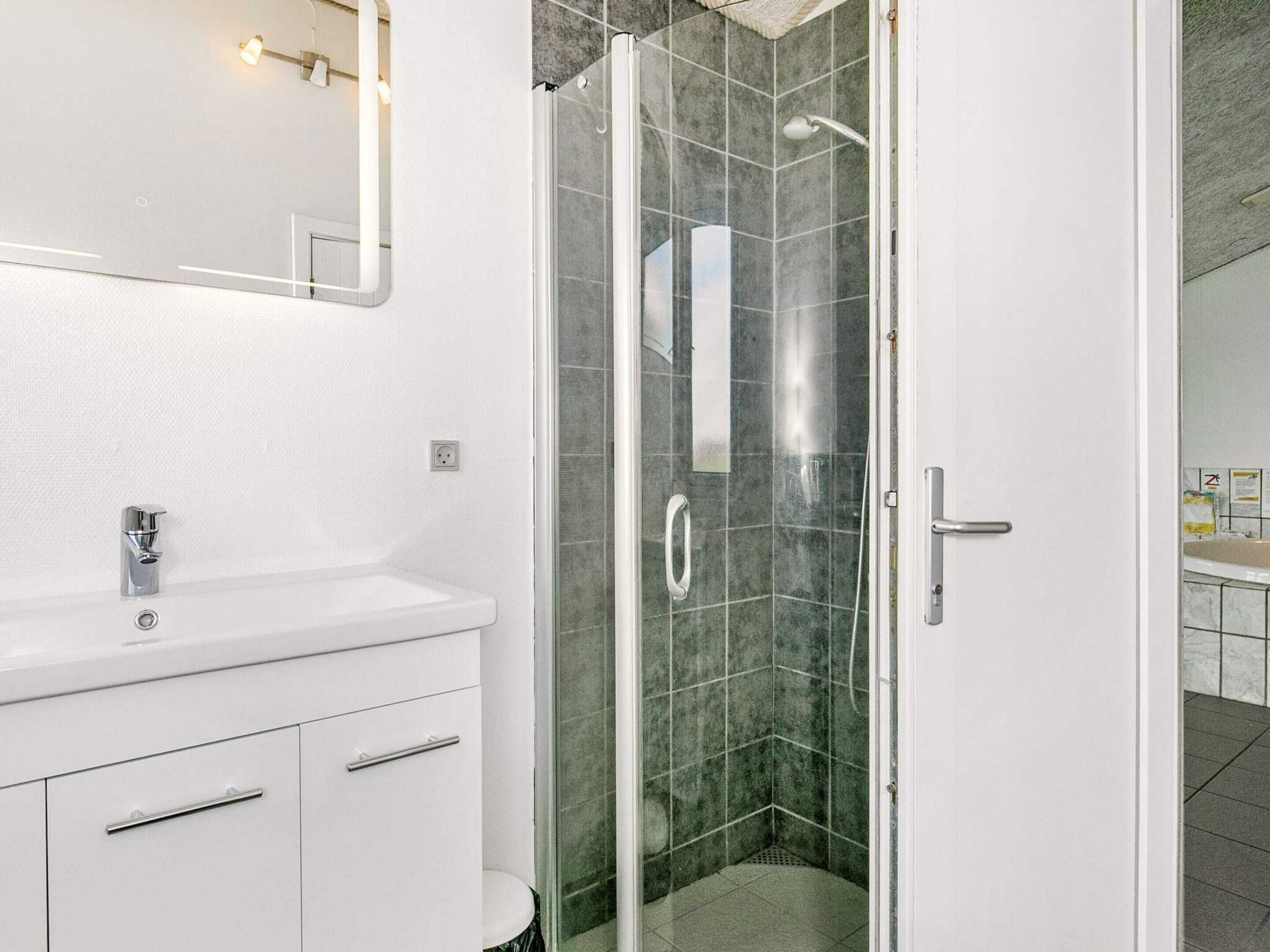 A modern bathroom with a glass-enclosed shower, a white sink with chrome fixtures, and a mirror above the sink.