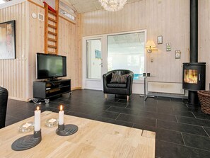A cozy living room with a TV, a fireplace, and a comfortable chair.