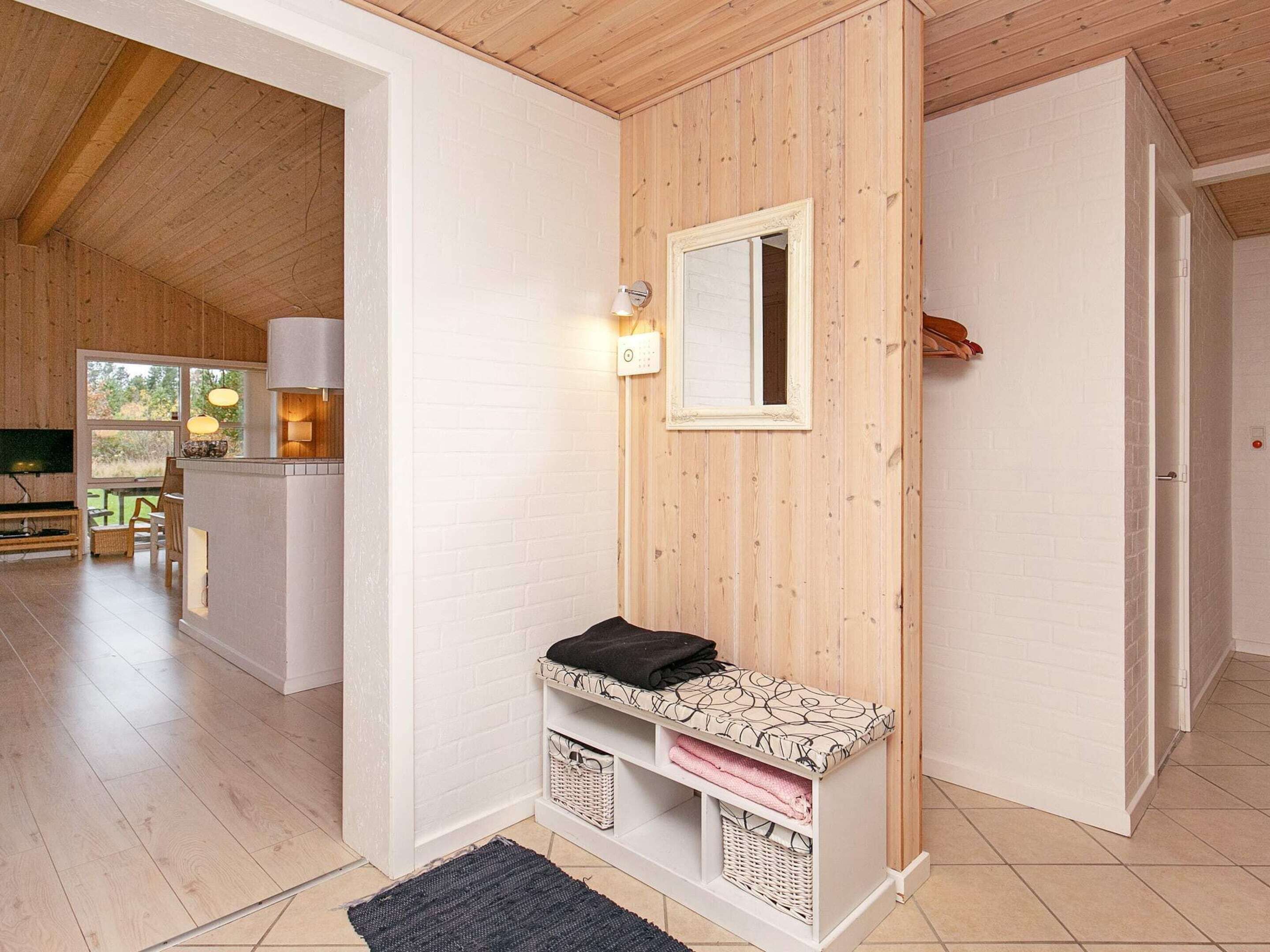 A modern bathroom with a wooden vanity, a mirror, and a small shelf with towels.