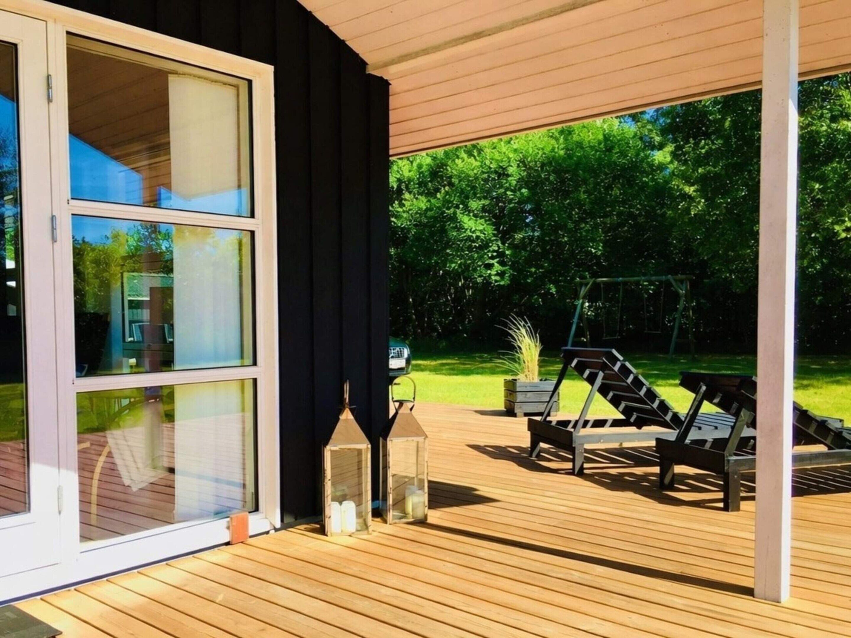 Un espace extérieur abrité, doté d’une terrasse en bois, de deux chaises longues et d’une balançoire.