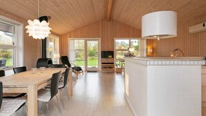 A spacious kitchen with a large island, wooden ceiling, and a view to the outdoors. - 4 Star Holiday Home in Jerup (Jerup)