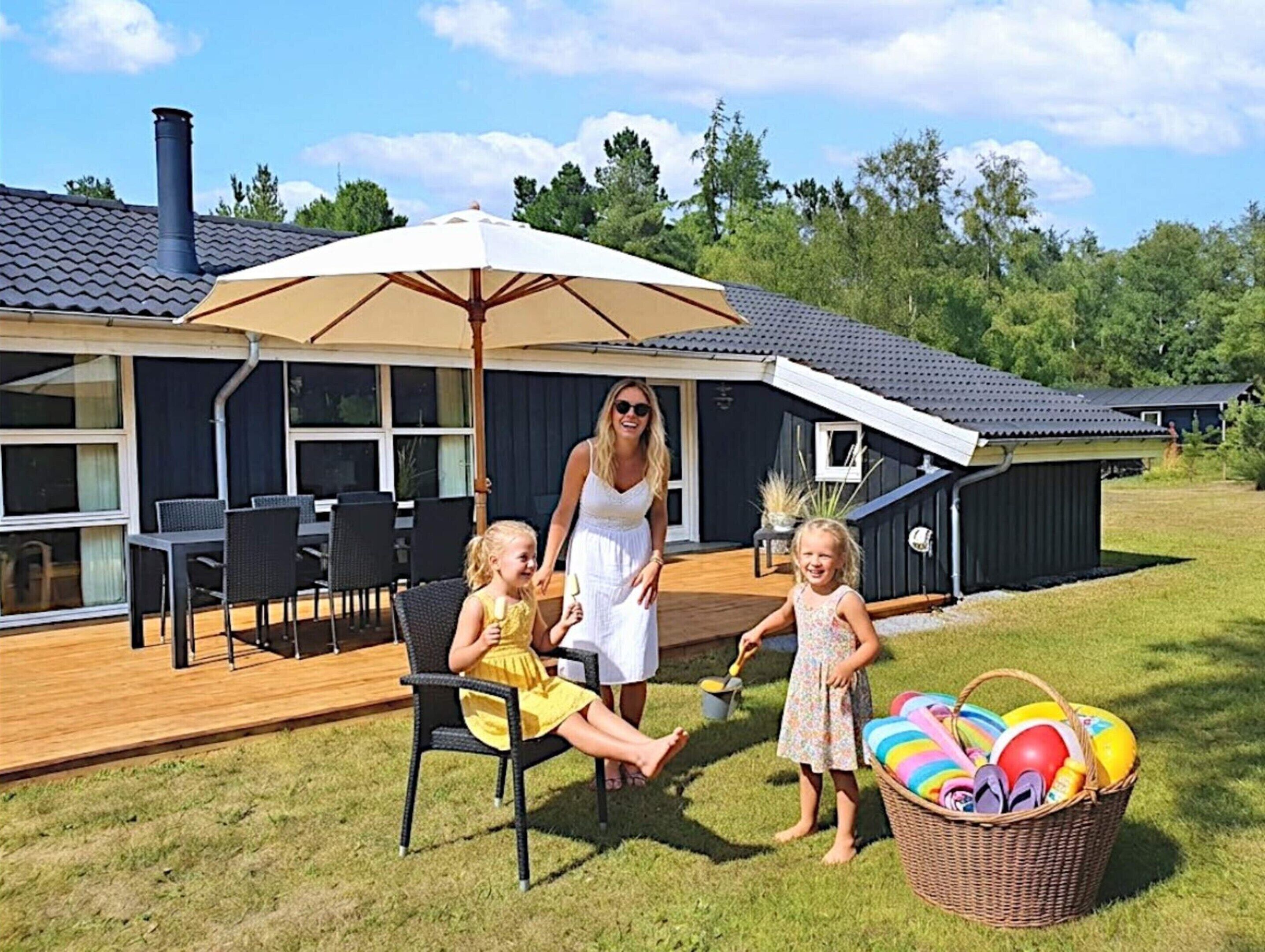 Une terrasse dotée de mobilier d’extérieur, d’un espace abrité et d’un bâtiment à l’extérieur sombre et muni d’une cheminée.