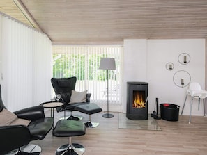 A modern living room with a wood-burning stove, leather sofas, and a glass coffee table.