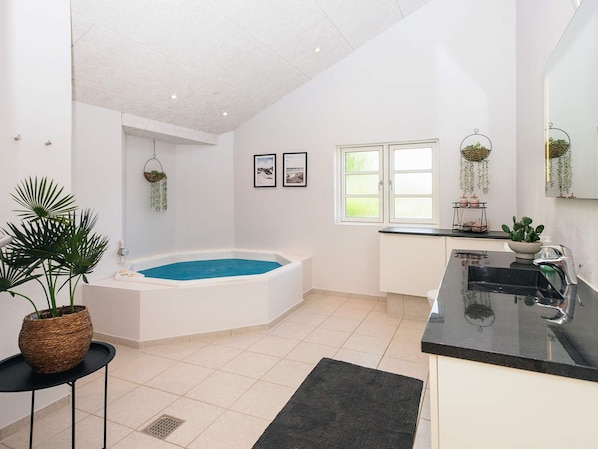 A modern bathroom with a bathtub, a sink, and a window.
