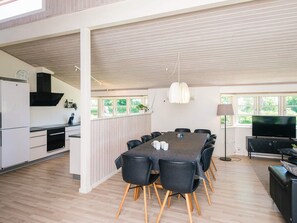 A modern kitchen with a refrigerator, stove, and dining area with a table and chairs.