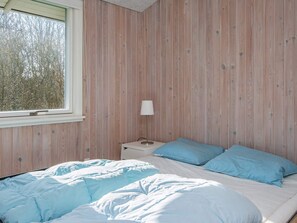 A bedroom with a bed, a nightstand, a lamp, and a window.