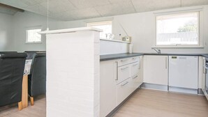 A modern kitchen with white cabinets, a built-in refrigerator, and a window providing natural light.