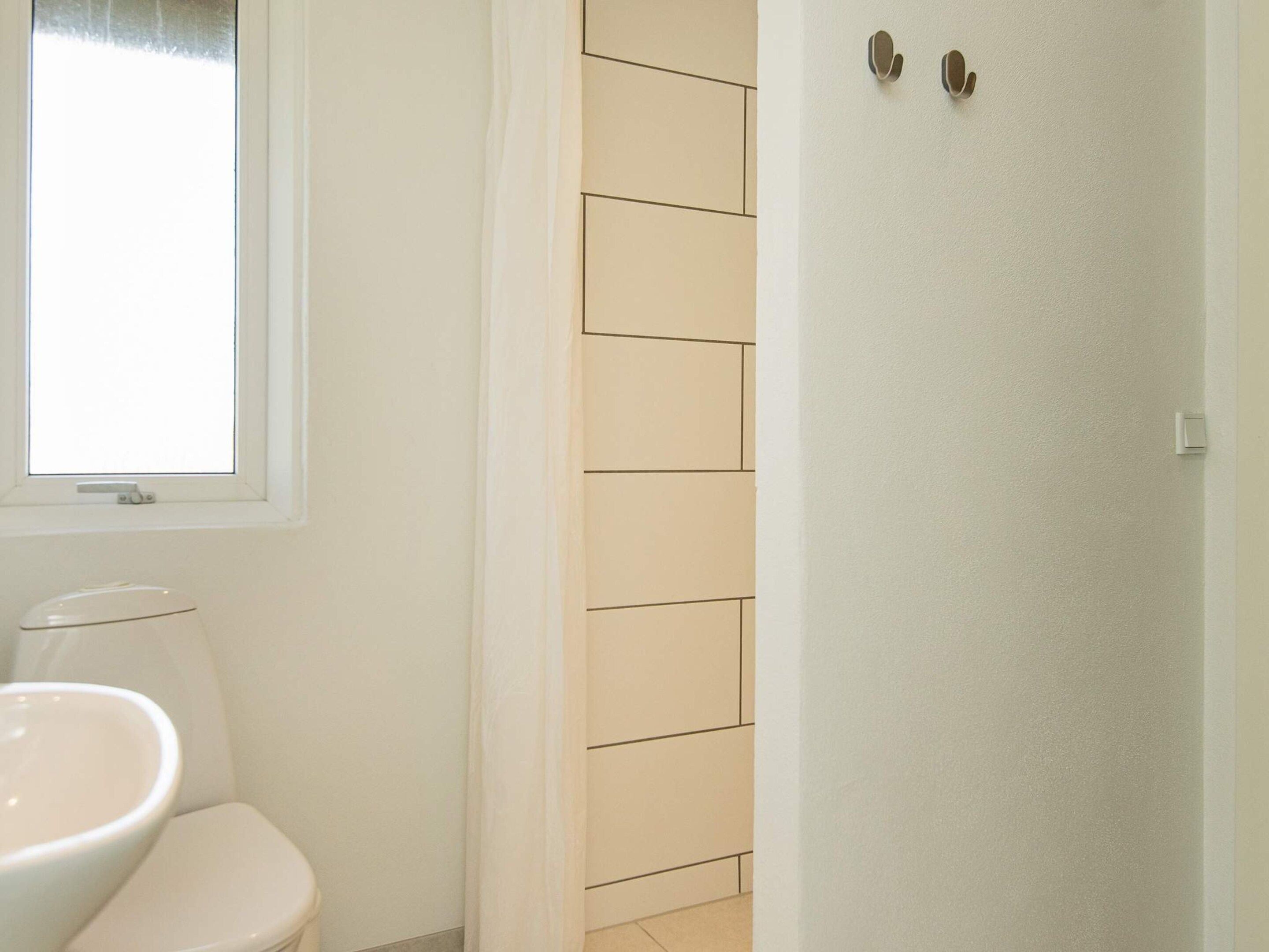 A bathroom with a toilet, a sink, and a window.