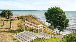 A wooden staircase leading to a beach with a picnic table nearby.