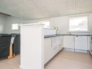 A kitchen with white cabinets, a refrigerator, a sink, and a window.