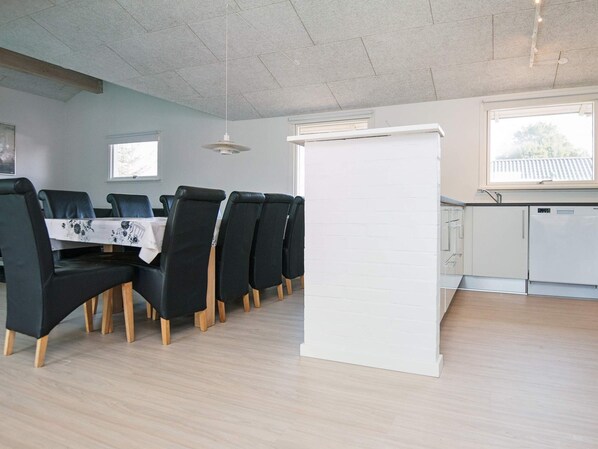 A dining area with a table set for four, surrounded by chairs, and a kitchen area with a refrigerator and cabinets.