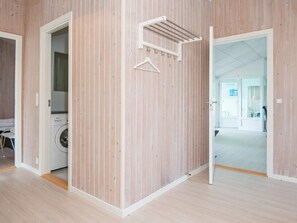 A room with a wooden panel wall, a hanging clothes rack, and a washing machine in the corner.