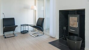 A modern living room with a fireplace, two black chairs, a small round table, and a floor lamp.