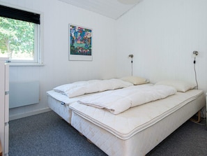 A bedroom with a single bed, a radiator, a window, and a wall-mounted power outlet.