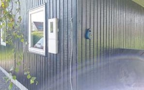 Un bâtiment avec un revêtement vertical, une fenêtre avec un cadre blanc et un petit objet bleu sur le mur.