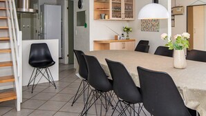 Ett modernt kök med en matplats, med ett stort bord, svarta stolar och en vit hänglampa.